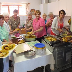 Die groep dames van die NG Vrouediens se Uitreikaksie â€œin aksieâ€ in die kombuis met die geurige ete 